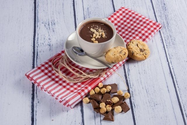 Chávena com chocolate e prato com bolachas
